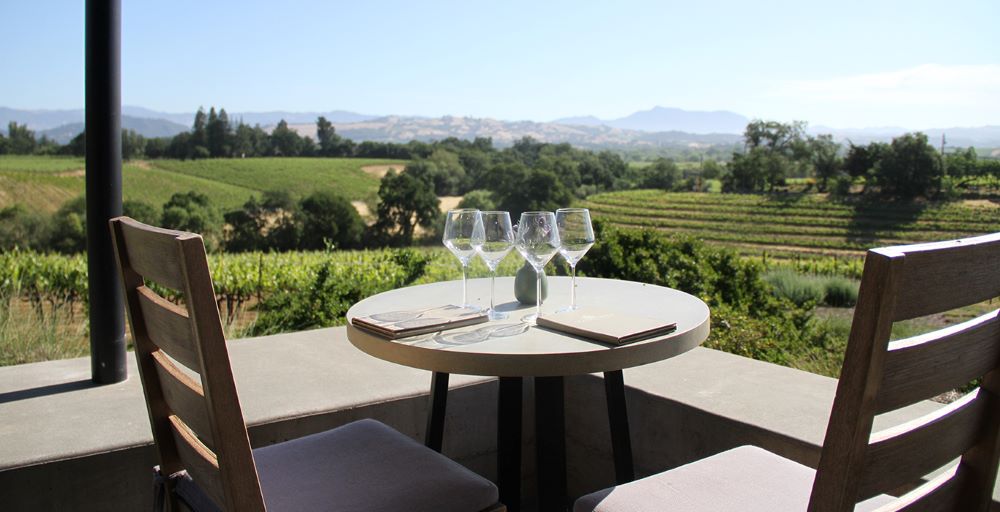 Four wine glasses and a table overlooking a vineyard in Healdsburg