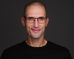 Julius Solaris in a black shirt against a dark background.