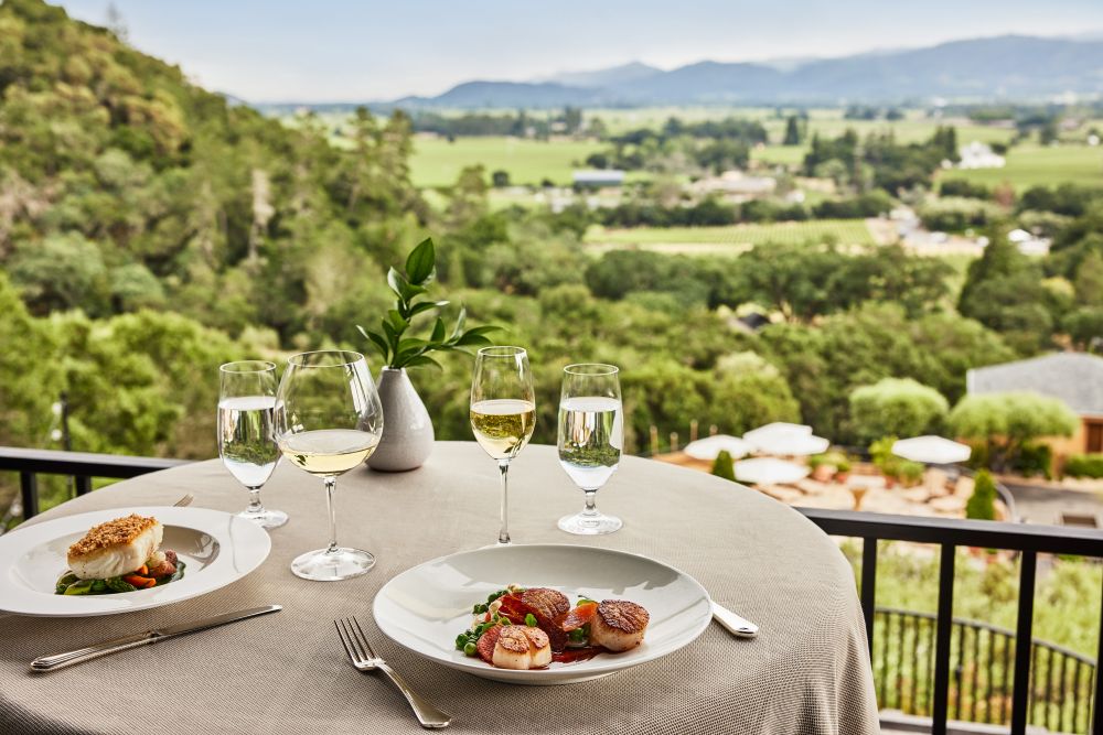 Photo of scallops and wine in front of a vineyard.