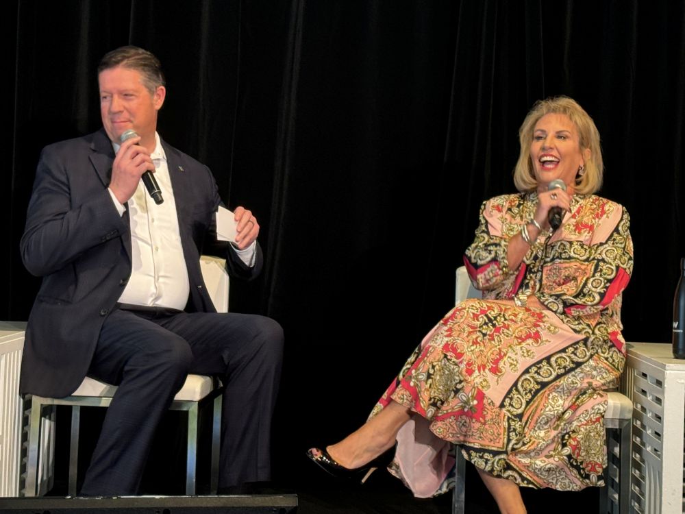 Photo of Anna Marie Presutti (right) with San Francisco Travel Board Chair John Anderson, sitting on a stage.th San Fr