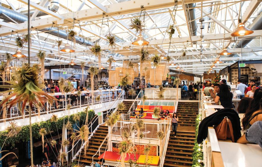 Anaheim Packing House interior, with a giant staircase and people eating on each side on the second floor.