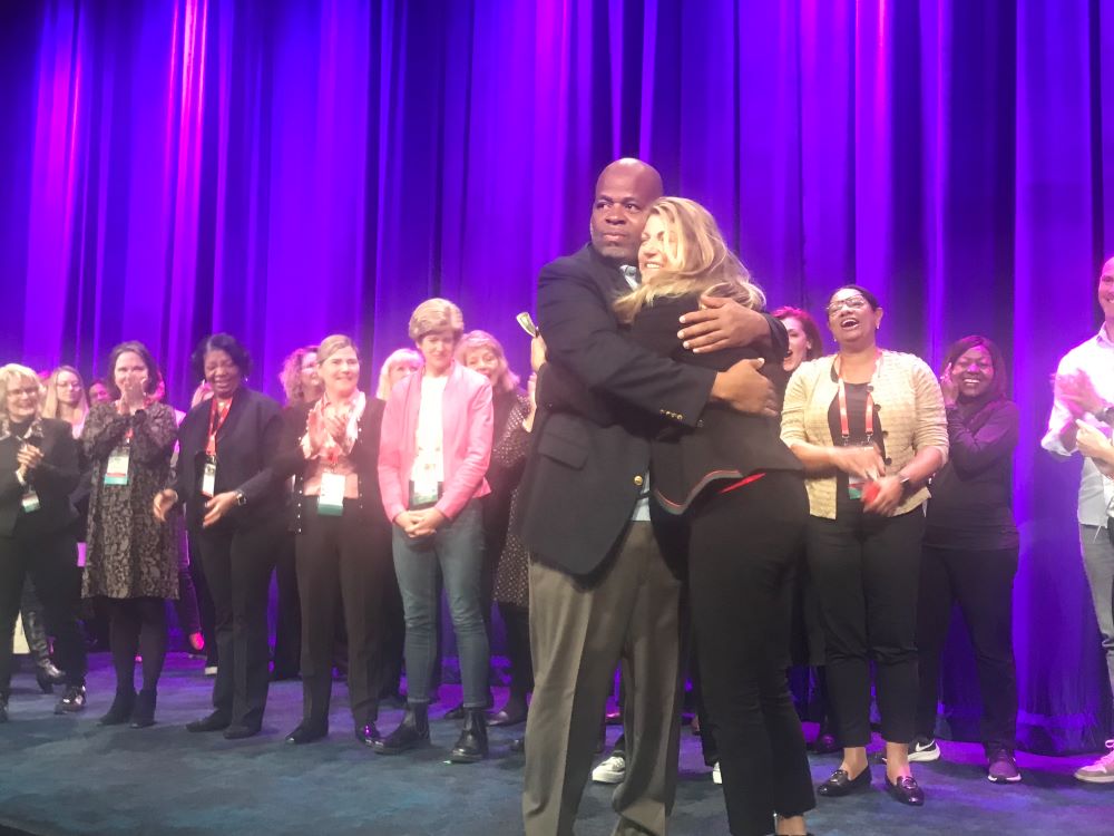 Speaker Andre Norman hugs SITE CEO Annette Gregg following his keynote speech.