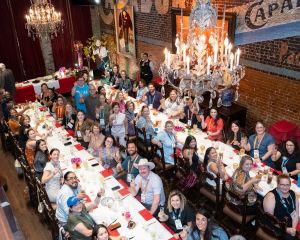 Photo of two large rectangular tables with attendees dining.