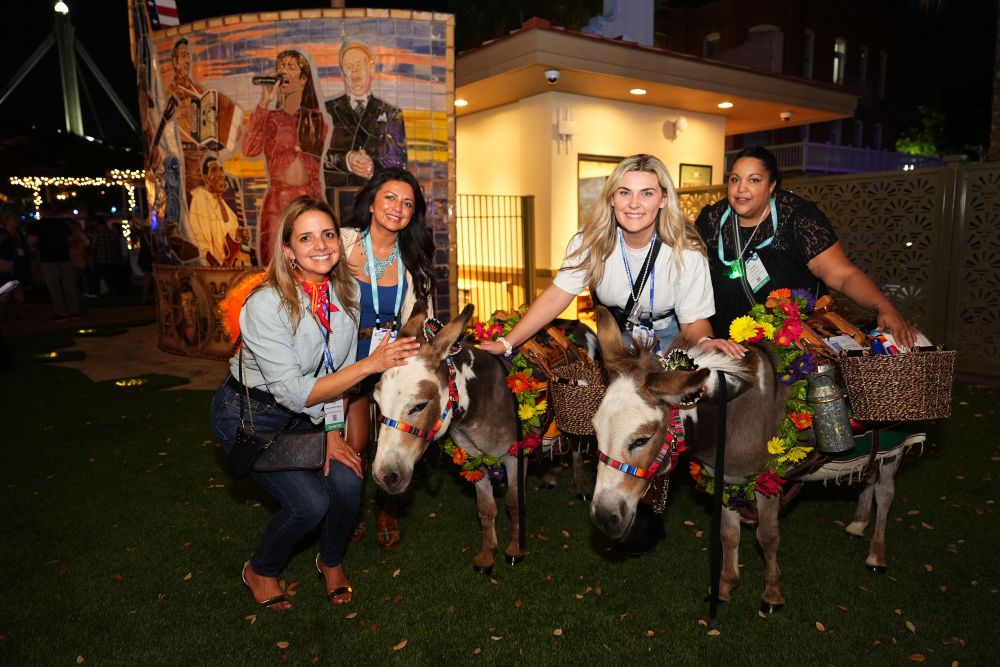 Four meeting attendees posing with donkeys.