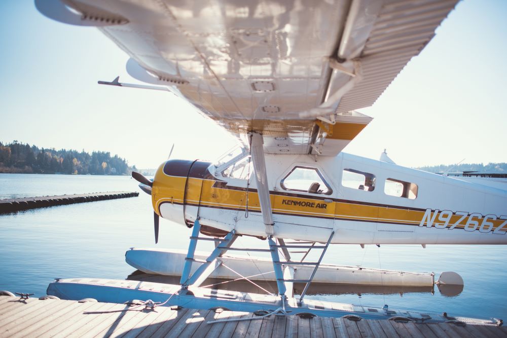 Photo of Kenmore Air de Havilland Beaver seaplane off of a dock in the sun,