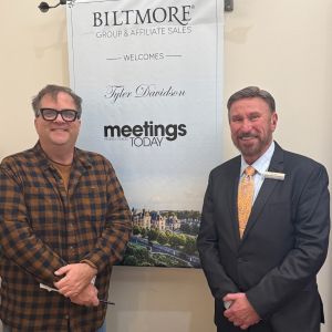 Tyler Davidson and Tim Hill standing in front of a banner about Meetings Today's visit to The Inn on Biltmore Estate.