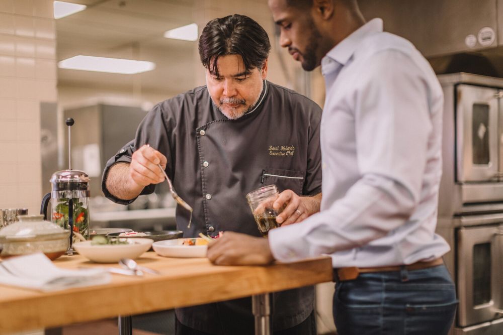 photo of Chef Hollands in the kitchen demonstrating the preparate of a dish.