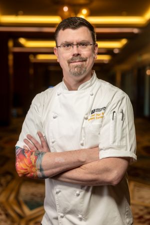 Mathew J. Bishop, standing in a chef's uniform.