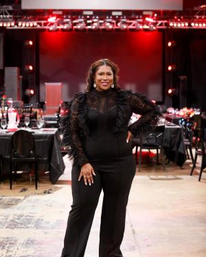 Photo of Cherrell Woodley, standing with a red background.