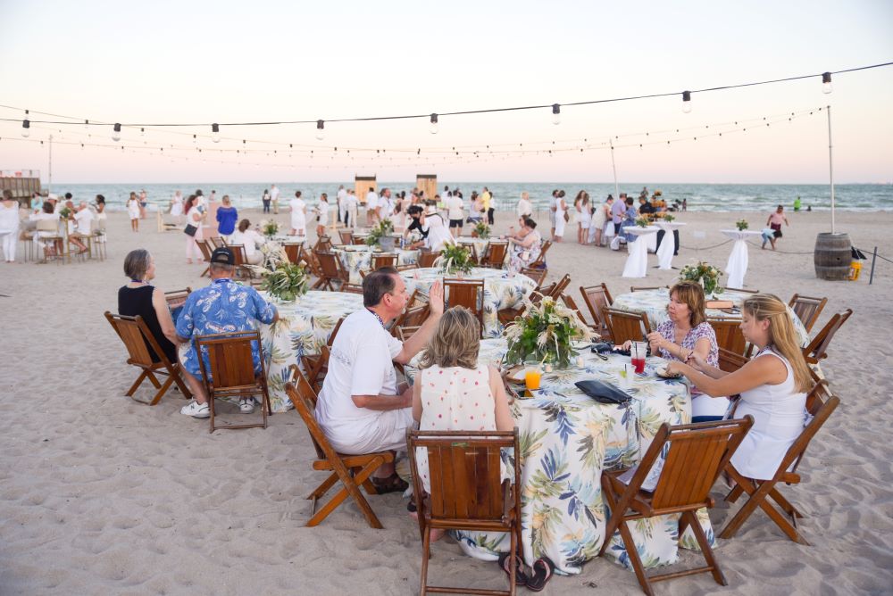 Photo of people sitting at banquet rounds on beach in Corpus Christi.