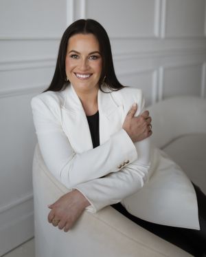 Courtney Stanley, sitting on a white couch in front of a white background