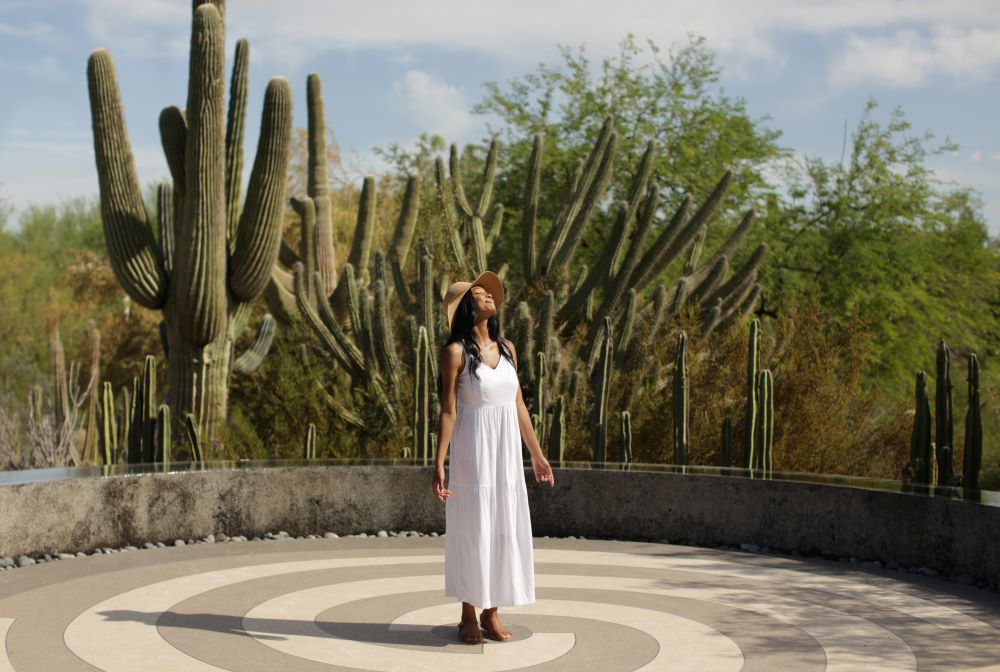 Photo of woman standing amongst desert plants at Desert Botanical Garden.