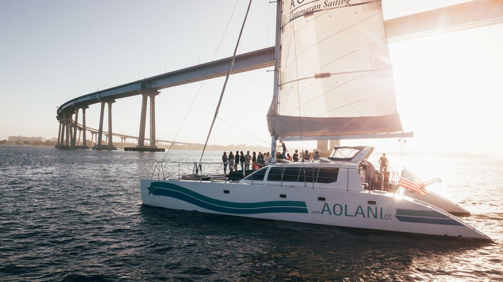 A group on a sailboat under Coronado Bridge.