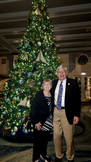Dean Miller and his wife Gwen standing in front of a Christmas tree.