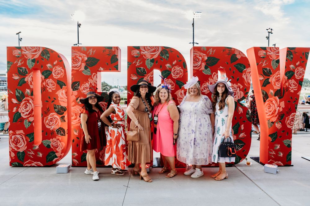 Photo of attendees standing in front of DERBY sign at Churchill Downs at MPI WEC.