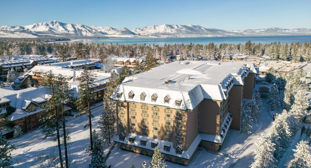 Exterior photo of Margaritaville Resort Lake Tahoe in winter, with the lake in the background.
