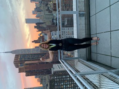 Image of Maria Grasso standing on a roof flexing her biceps.