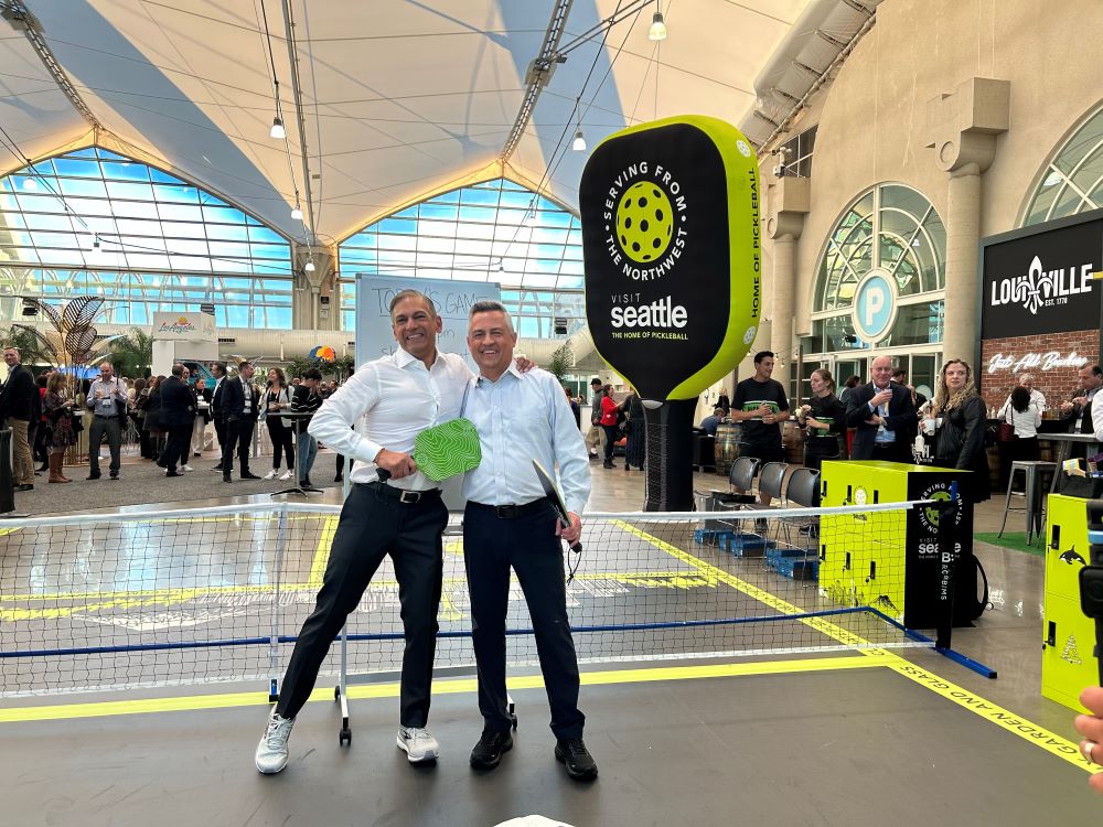 Photo of PCMA's Sherrif Karamat and Leonard Hoops standing on the Visit Seattle pickleball court at PCMA Convening Leaders 2024.