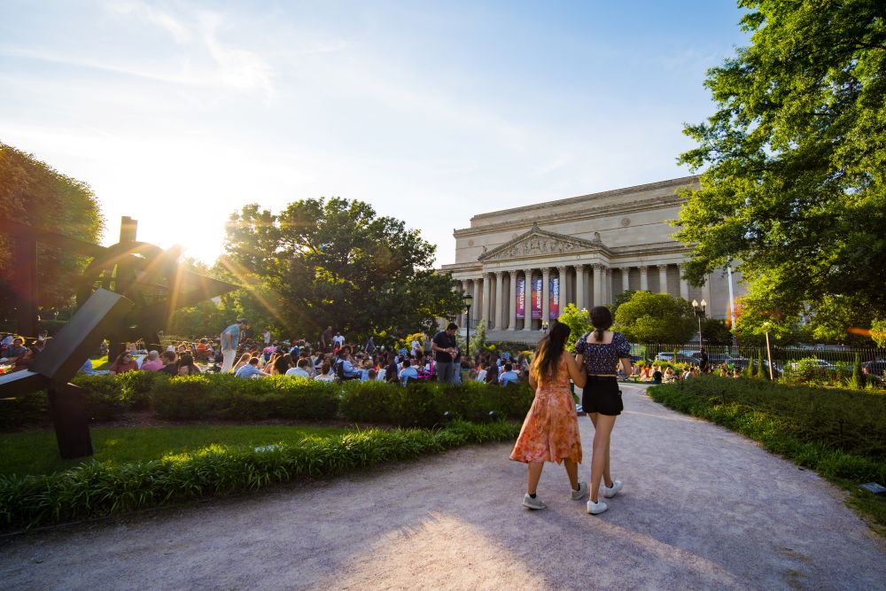 Photo of two women walking into a concert at Jazz in the Garden at the NGA Sculpture Garden.