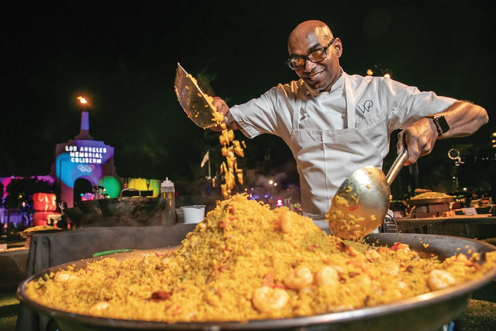 Photo of Wolfgang Puck Catering chef making paella at Adobe MAX Bash.,