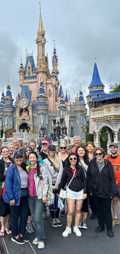 Jonathan Alder poses with a client group in front of Disney's Magic Kingdom castle