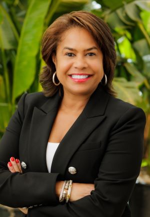 Photo of Julie Coker, standing with plants in the background.