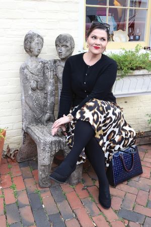 Photo of KiKi L’Italien sitting on a bench looking away from the camera.