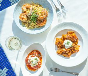 Three Linguine by the Sea entrees on white plates and a white tablecloth.