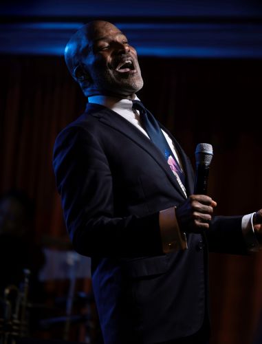 Lonnie McFadden singing into a microphone at a jazz club