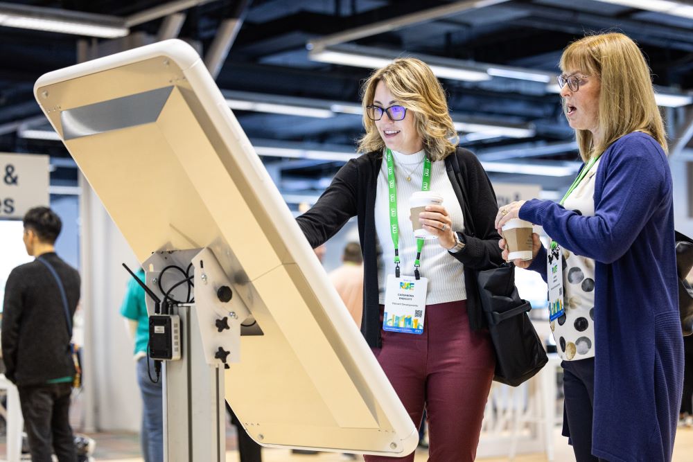 Photo of two women at an MRI Software event accessing a giant smart phone.