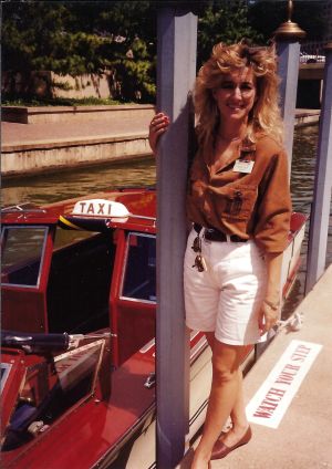 Photo of Maura Gast from the 1980s, standing next to a water taxi, on a dock.