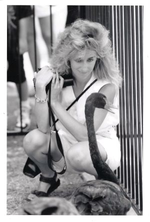 Photo of Maura Gast, holding a camera, with black swans.