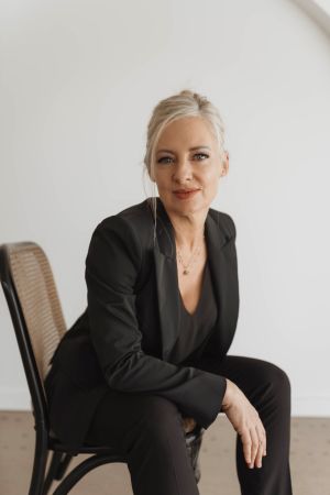 Photo of author in a black suit sitting in a brown chair.