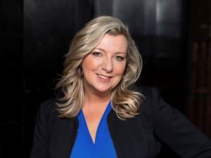 Photo of Nicola Kastner in blue shirt and black jacket.