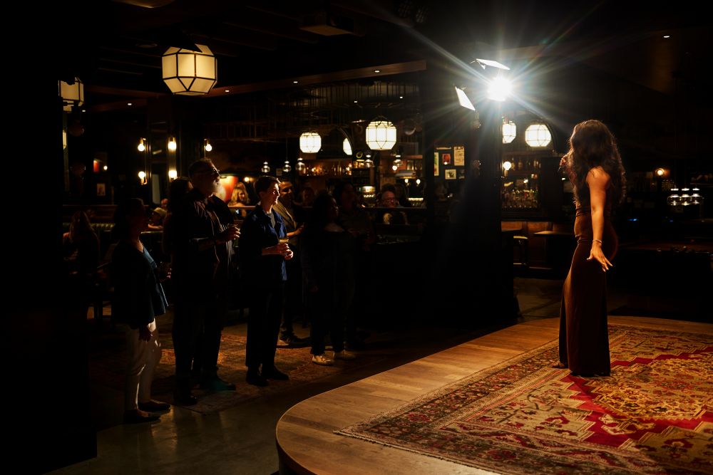 A crowd watches a jazz singer perform on stage at Nighthawk jazz club
