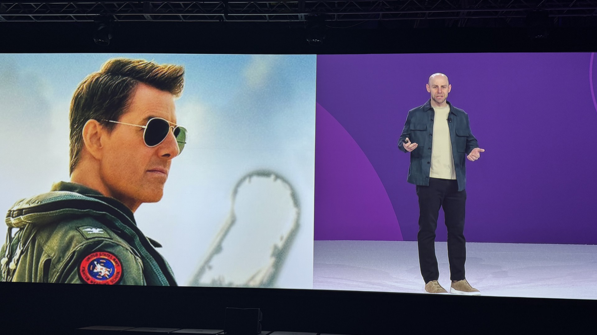 Photo of Adam Grant onstage, with an image of Tom Cruise from Top Gun at the left.