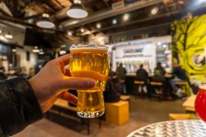 Photo of a hand holding a glass of beer in Anaheim Packing District.