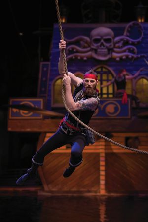 A pirate hanging hanging on to a rope on stage.