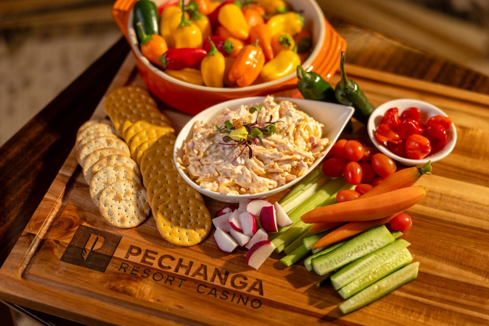 Photo of a cutting board with pimento dip, vegetables and crackers.