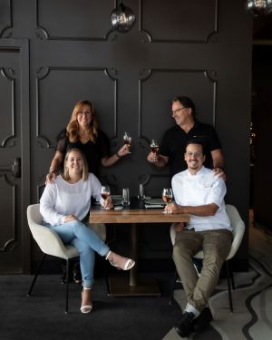 Photo of the team at Laurie Raphael restaurant, sitting at a table enjoying wine.