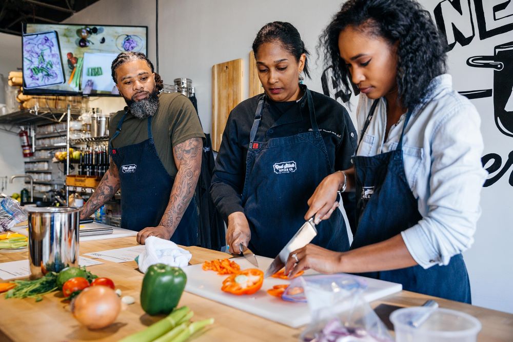 Group of three people cutting peppers during Red Stick Social cooking class