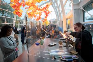Photo of woman watching a glass blowing demonstration at Refract: The Seattle Glass Experience.