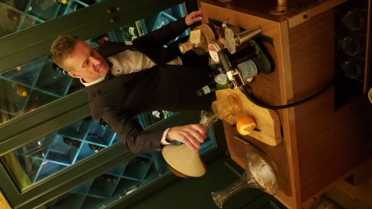 A bartender pouring a smoked old fashioned cocktails out of a decanter.