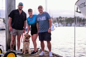 Deborah Gardner (center) standing with a two veterans and a dog on a dock.