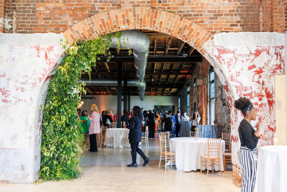 Photo of Laundry Building event, with a brick archway in the foreground and people gathered.