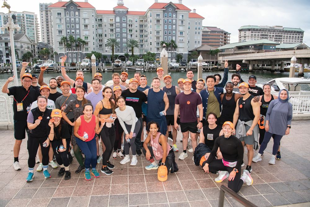 People in athletic gear posting in front of Tampa harbor.