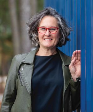 Photo of Tracy Stuckrath, standing next to a blue wall.