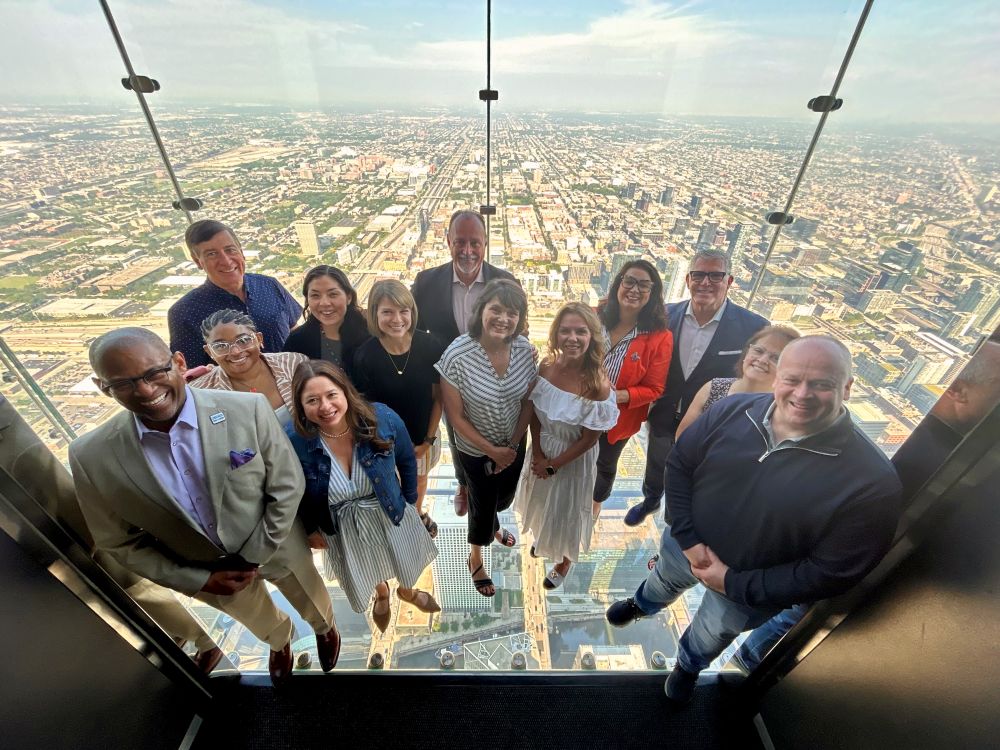 Meetings media and members from Choose Chicago, DI and Skydeck pose on the Willis Tower Skydeck Ledge