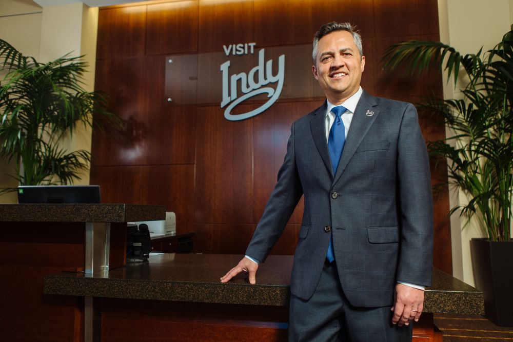 Photo of Leonard Hoops standing with his hand on a desk in the offices of Visit Indy.