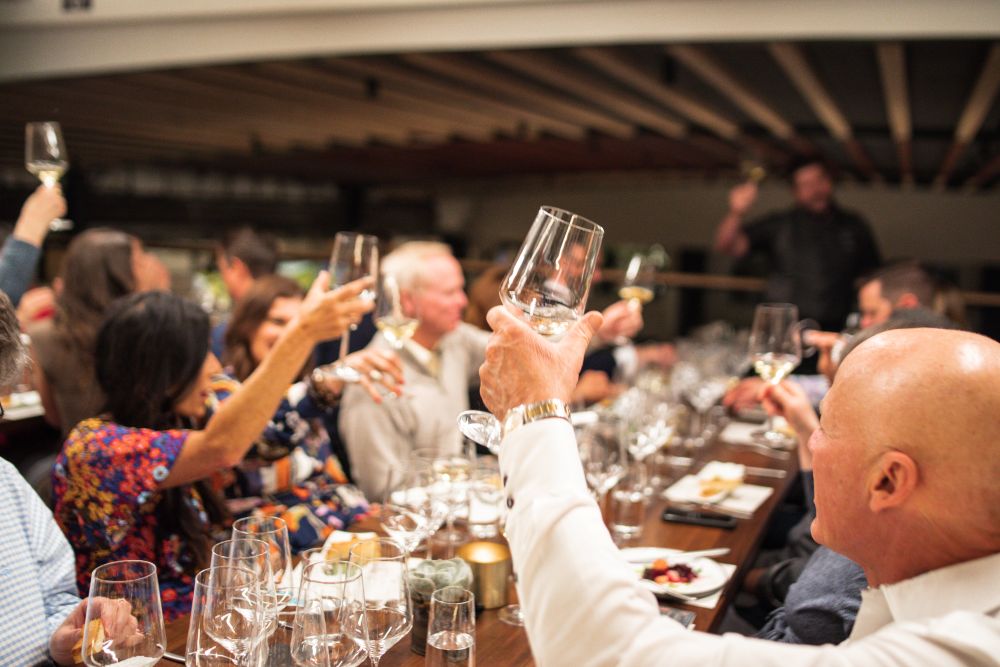 Photo of people holding up wine glasses during a tasting.